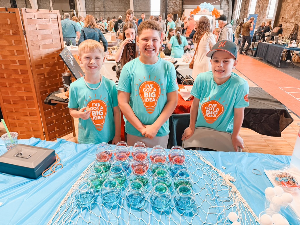 Three young founders at their carnival-game stand